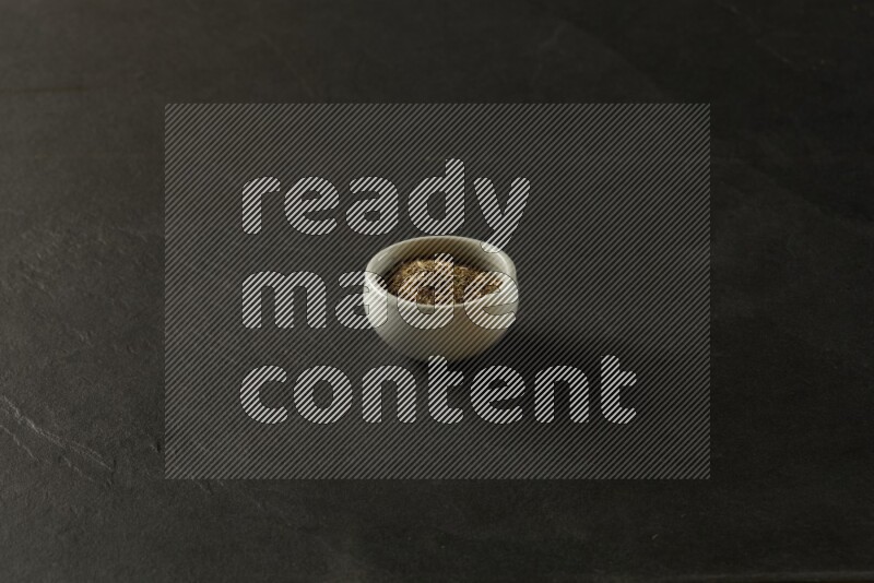 white ceramic round sauce bowl filled with herbs on grey textured countertop