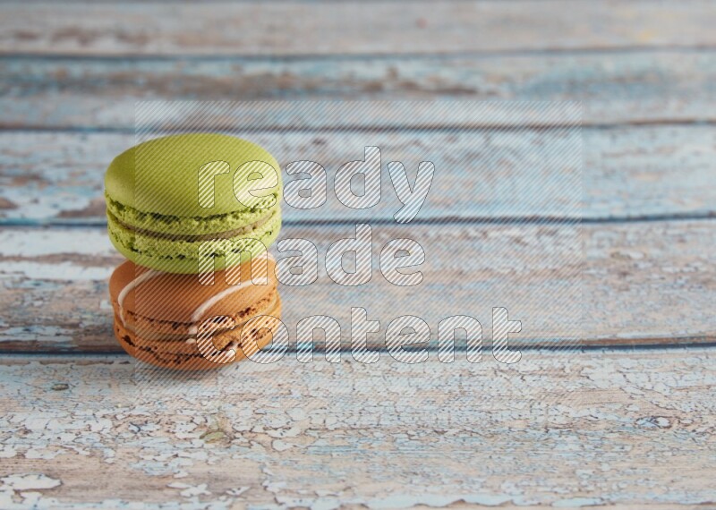 45º Shot of of two assorted Brown Irish Cream, and Green Pistachio macarons  on light blue background