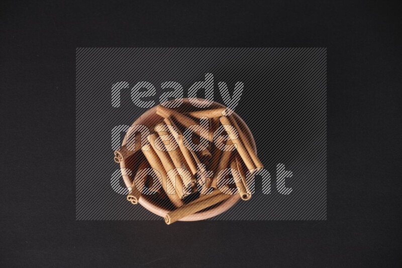 Cinnamon Sticks in a wooden bowl on black background