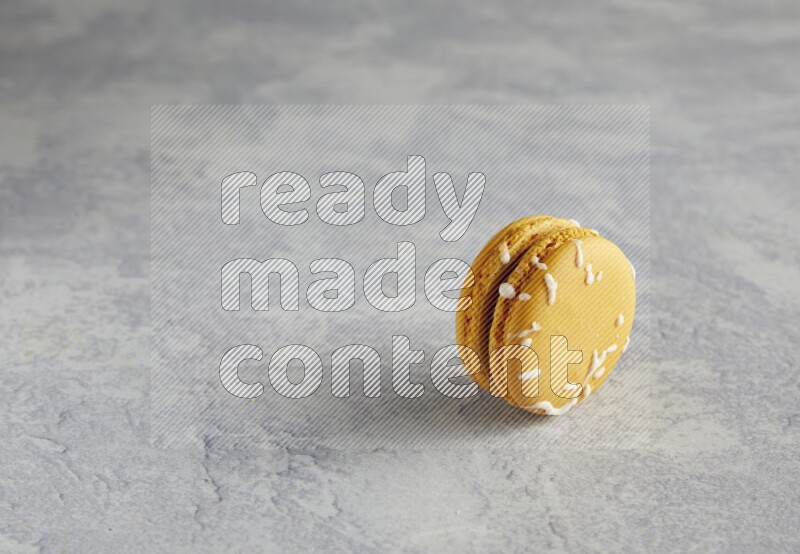45º Shot of Yellow Piña Colada macaron on white  marble background