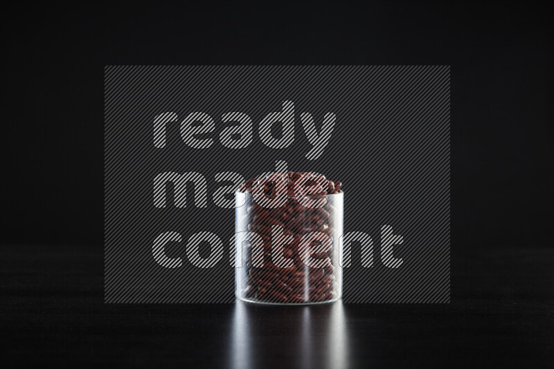 Red kidney beans in a glass jar on black background