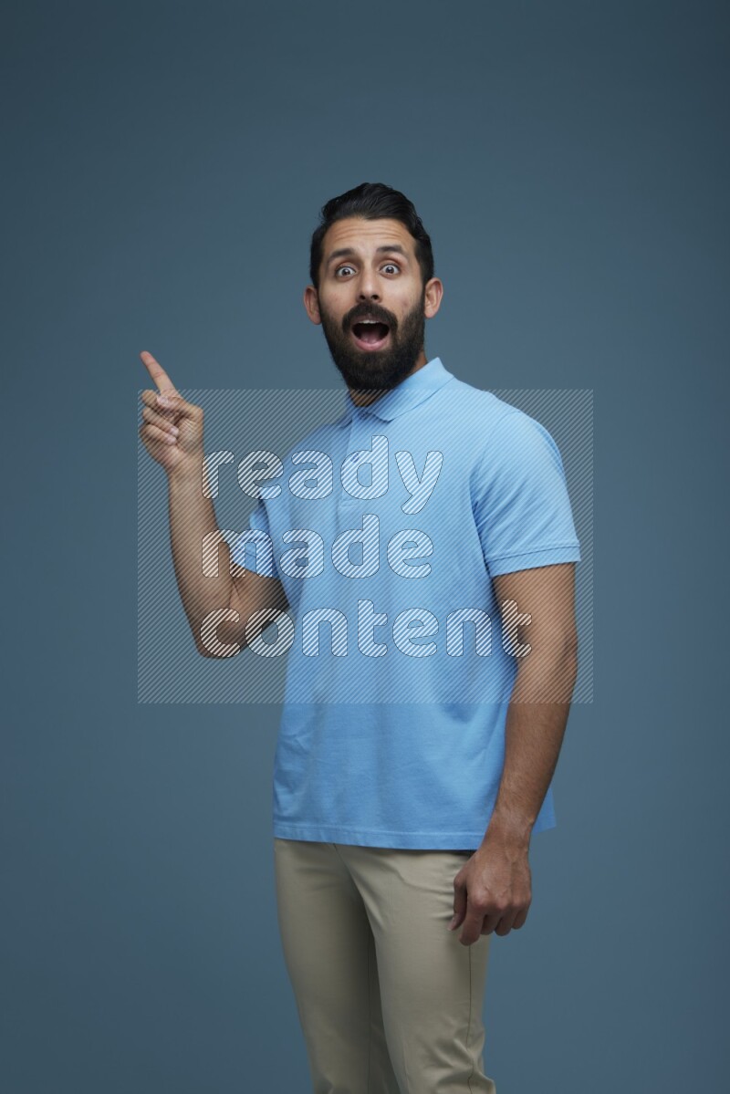 A man pointing  in a blue background wearing a Blue shirt
