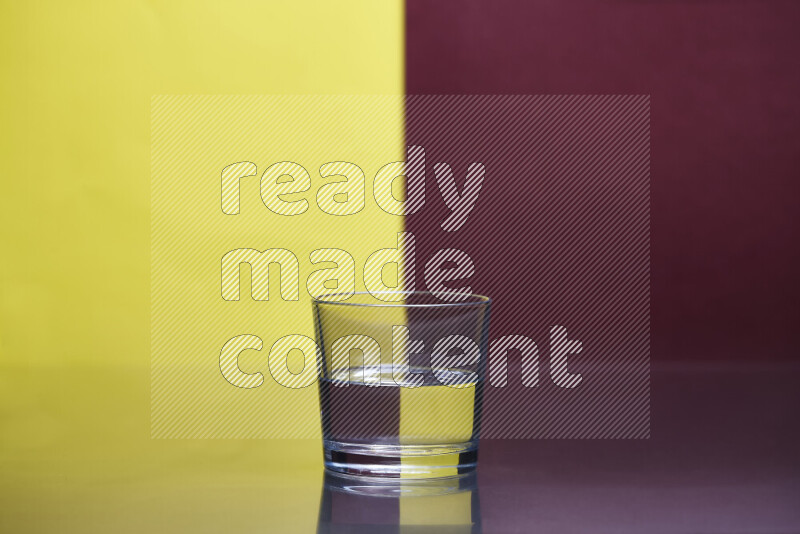 The image features a clear glassware filled with water, set against yellow and dark red background