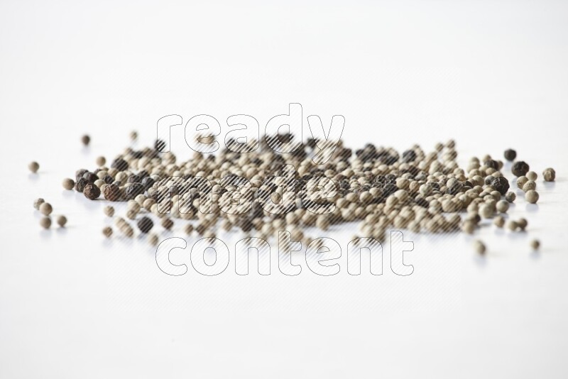 حبوب الفلفل المختلطة السوداء والبيضاء على أرضية بيضاء