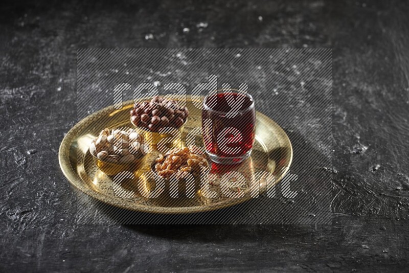 Nuts in metal bowls with Hibiscus on a tray in dark setup