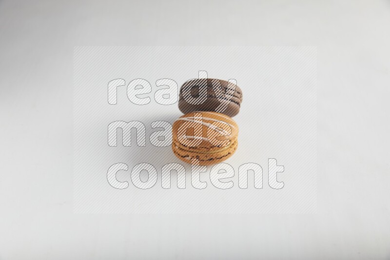 45º Shot of of two assorted Brown Irish Cream, and Brown Dark Chocolate macarons on white background