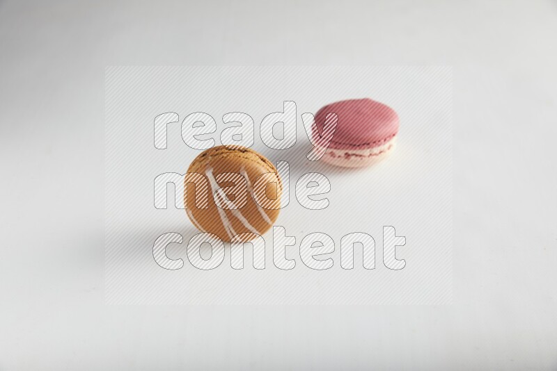 45º Shot of of two assorted Brown Irish Cream, and Pink Litchi Raspberry macarons on white background