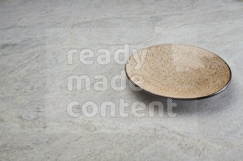 A beige pottery plate on grey marble background