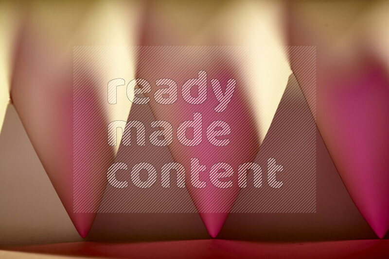 A close-up abstract image showing sharp geometric paper folds in pink gradients and warm tones