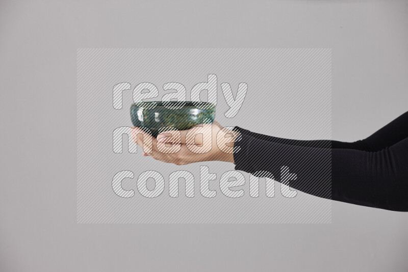 A woman in black abaya holding different pottery essentials in different positions