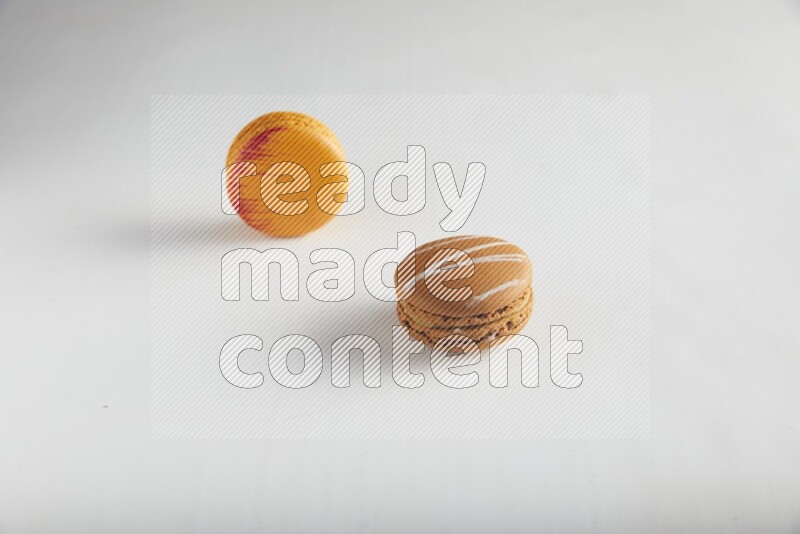 45º Shot of of two assorted Brown Irish Cream, and Orange Exotic macarons on white background