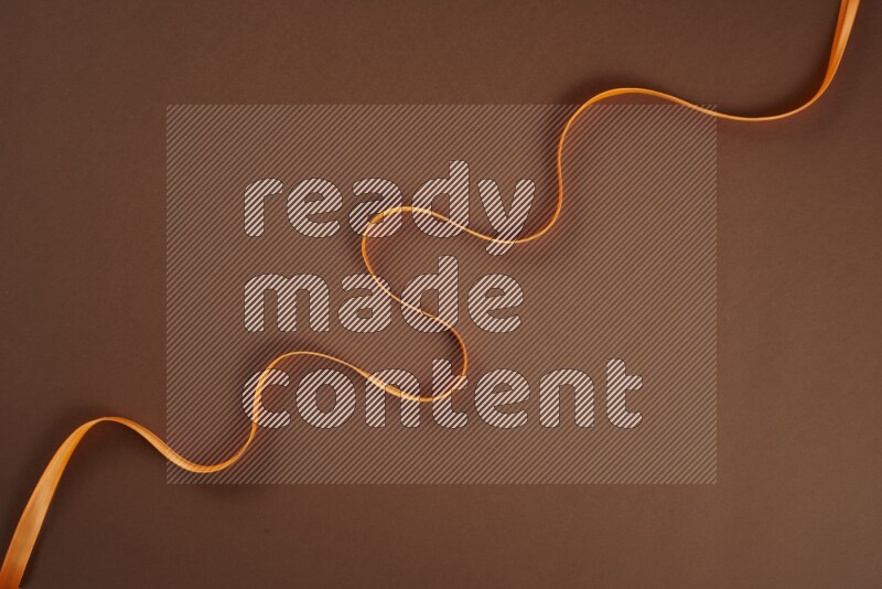 An orange collection of sewing and tailoring tools arranged on a brown background