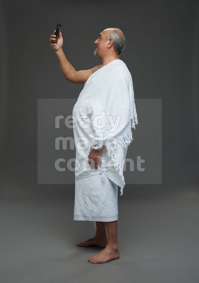 A man wearing Ehram Standing taking selfie on gray background