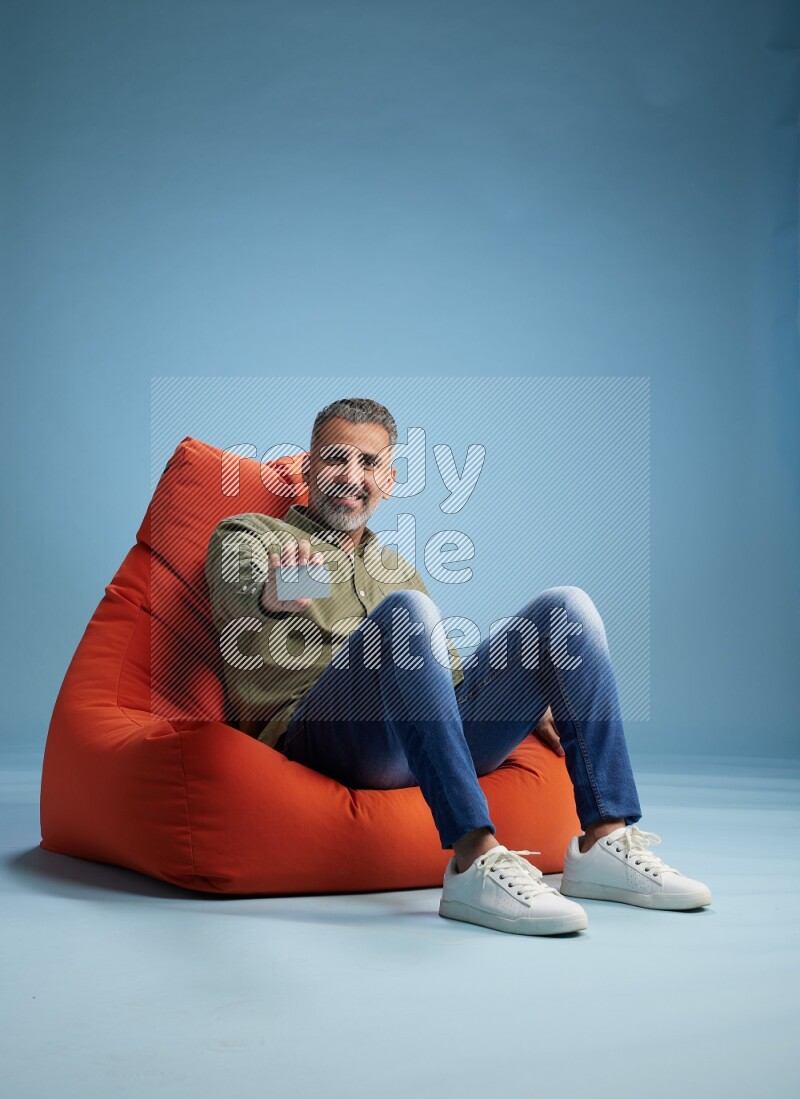 A man sitting on an orange beanbag and holding ATM card