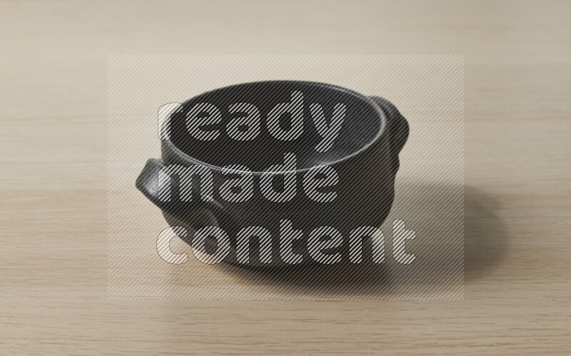 A black pottery bowl on light wooden background