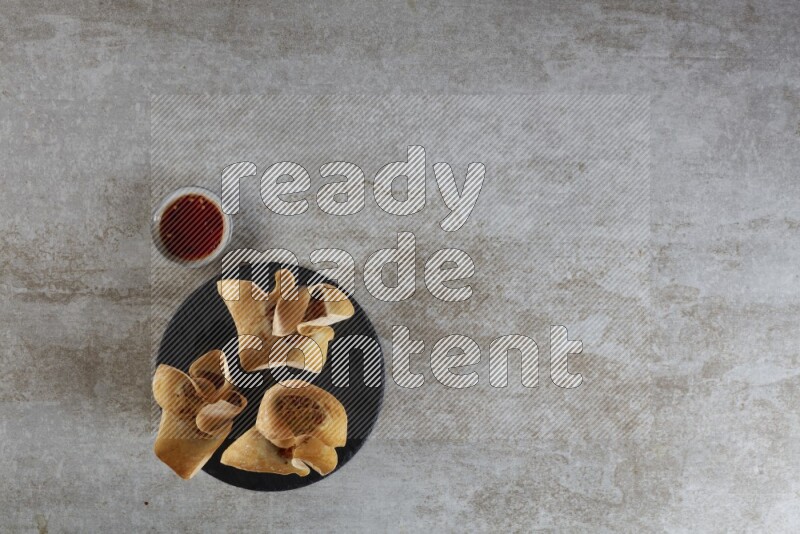 wonton cups with soy sauce ramkin on circle slate on grey textured counter top
