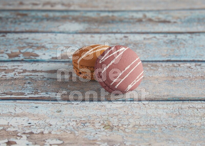 45º Shot of of two assorted Brown Irish Cream, and Red Poppy Flower macarons  on light blue background