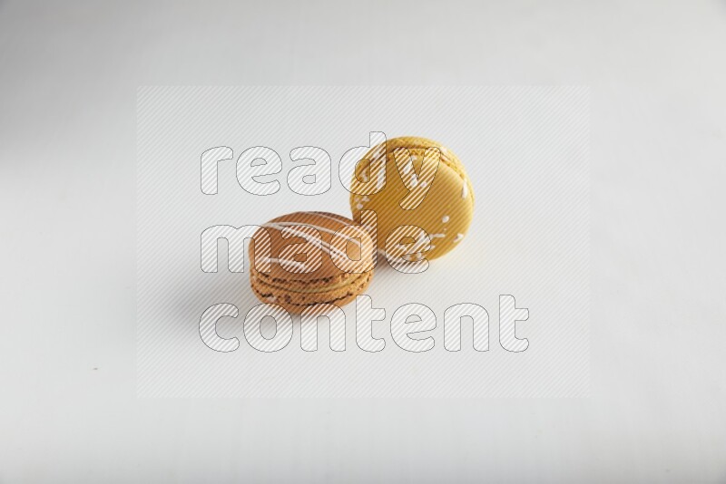 45º Shot of of two assorted Brown Irish Cream, and Yellow Piña Colada macarons on white background