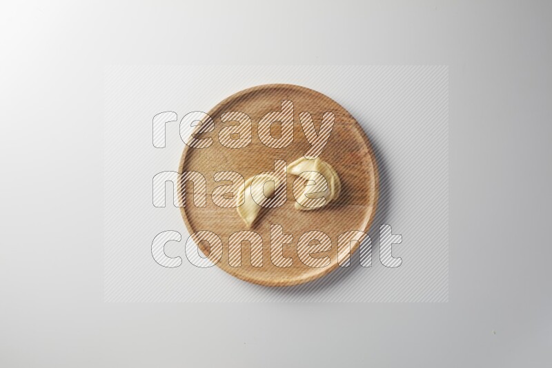 Three Sambosas on a wooden round plate on a white background