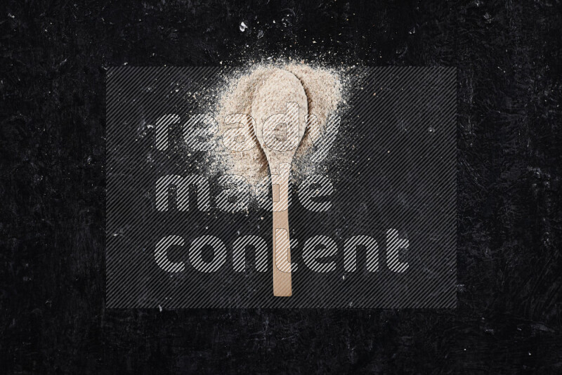 A wooden spoon full of onion powder on black background