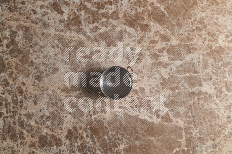 A small copper pot on beige marble background