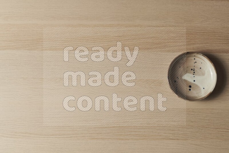 A multicolored pottery plate on light wooden background