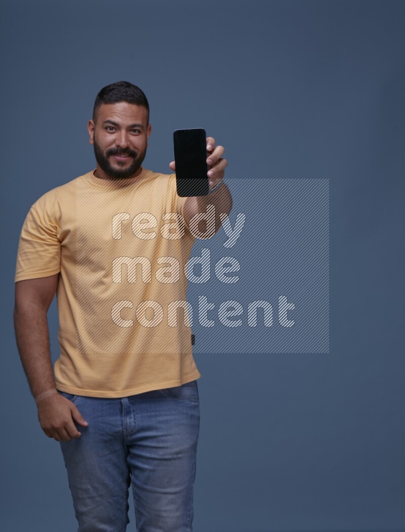A man Showing His Smart Phone on Blue Background wearing Orange T-shirt