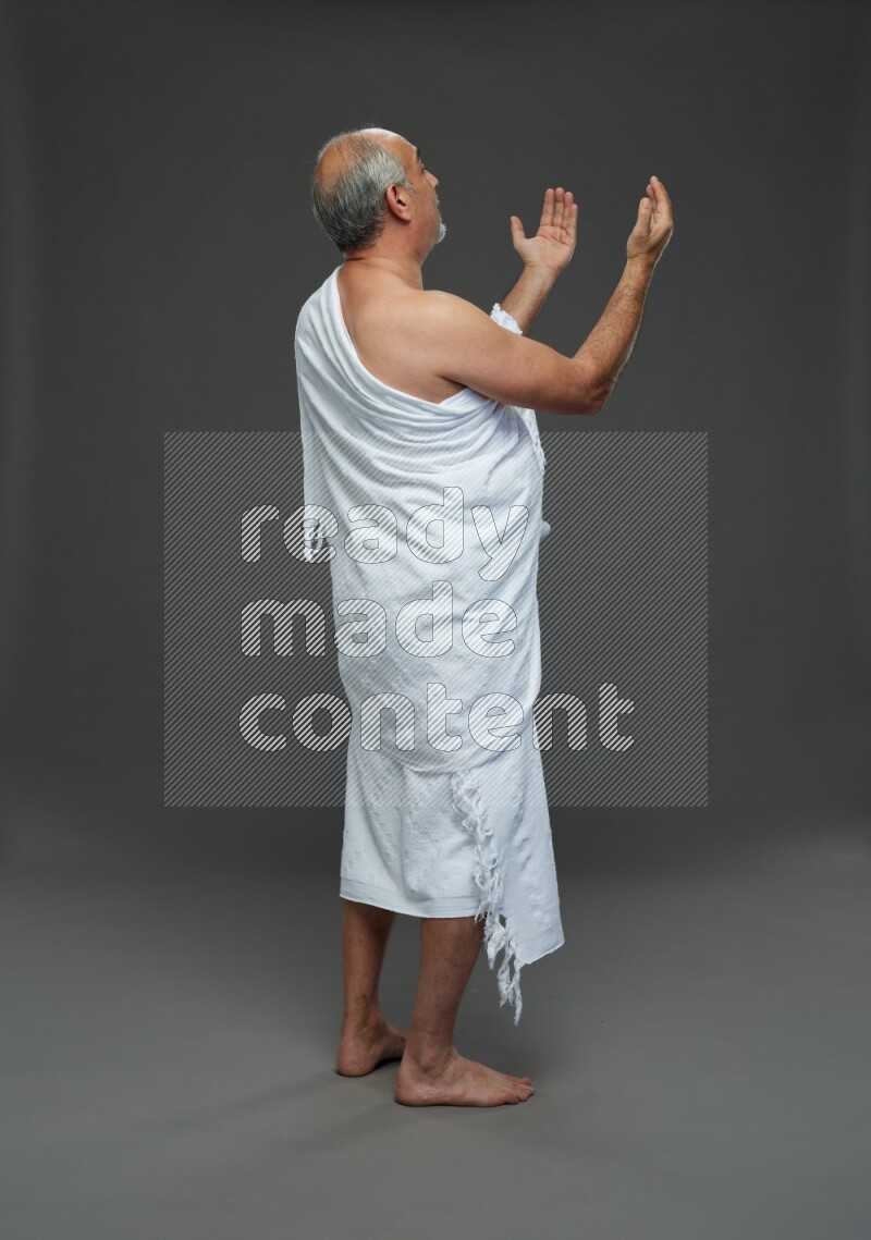 A man wearing Ehram Standing dua'a on gray background