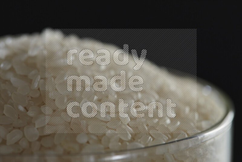 White rice in a glass jar on black background