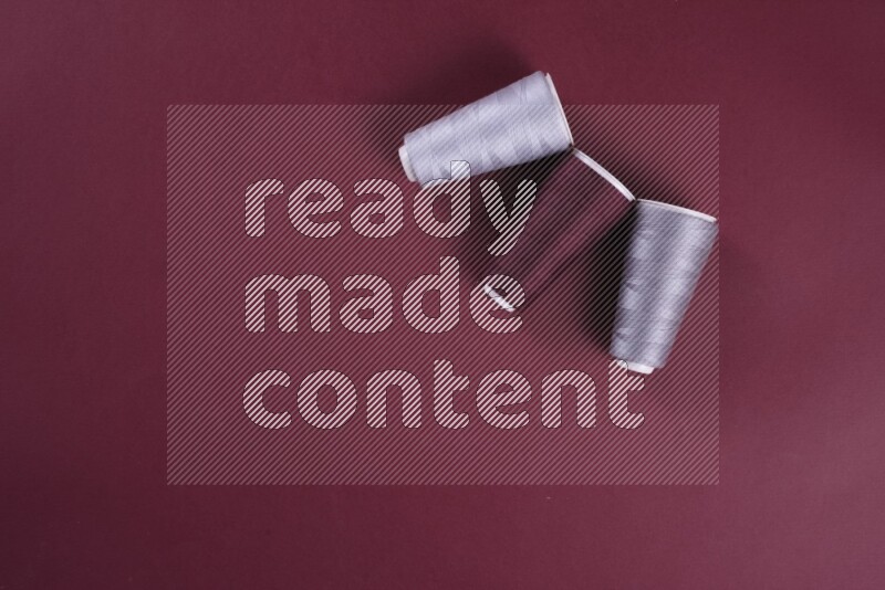 مجموعة من أدوات الخياطة والتفصيل رمادية اللون على خلفية حمراء