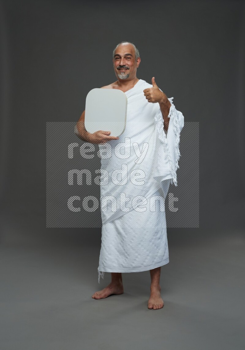A man wearing Ehram Standing holding social media sign on gray background