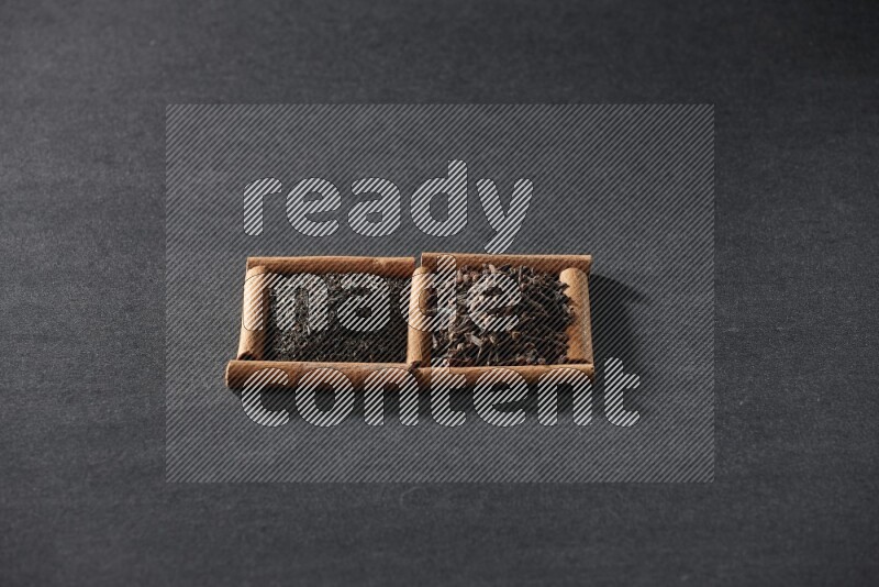 مربعان من أعواد القرفة ممتلئان بالشاي وحبوب القرنفل علي خلفية سوداء