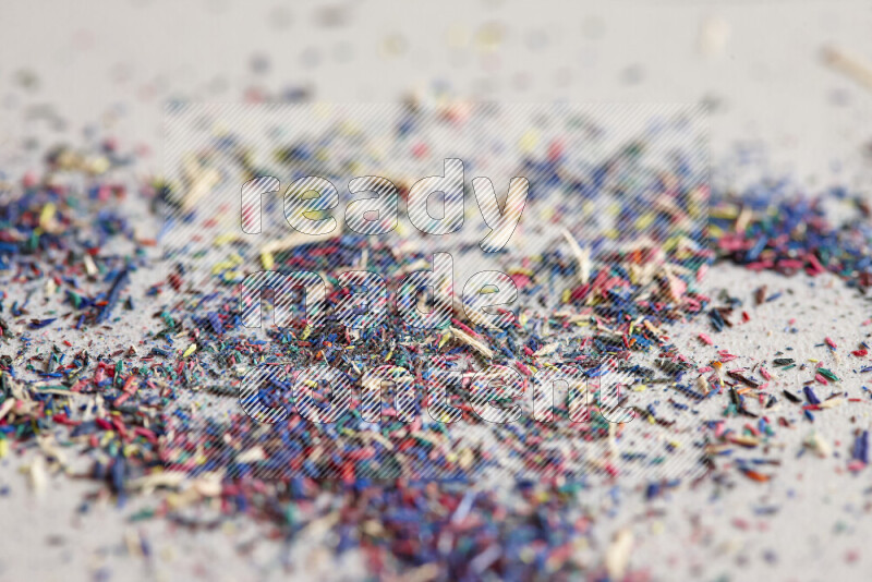 This image showcases a vibrant multicolored pencil shavings scattered on grey background