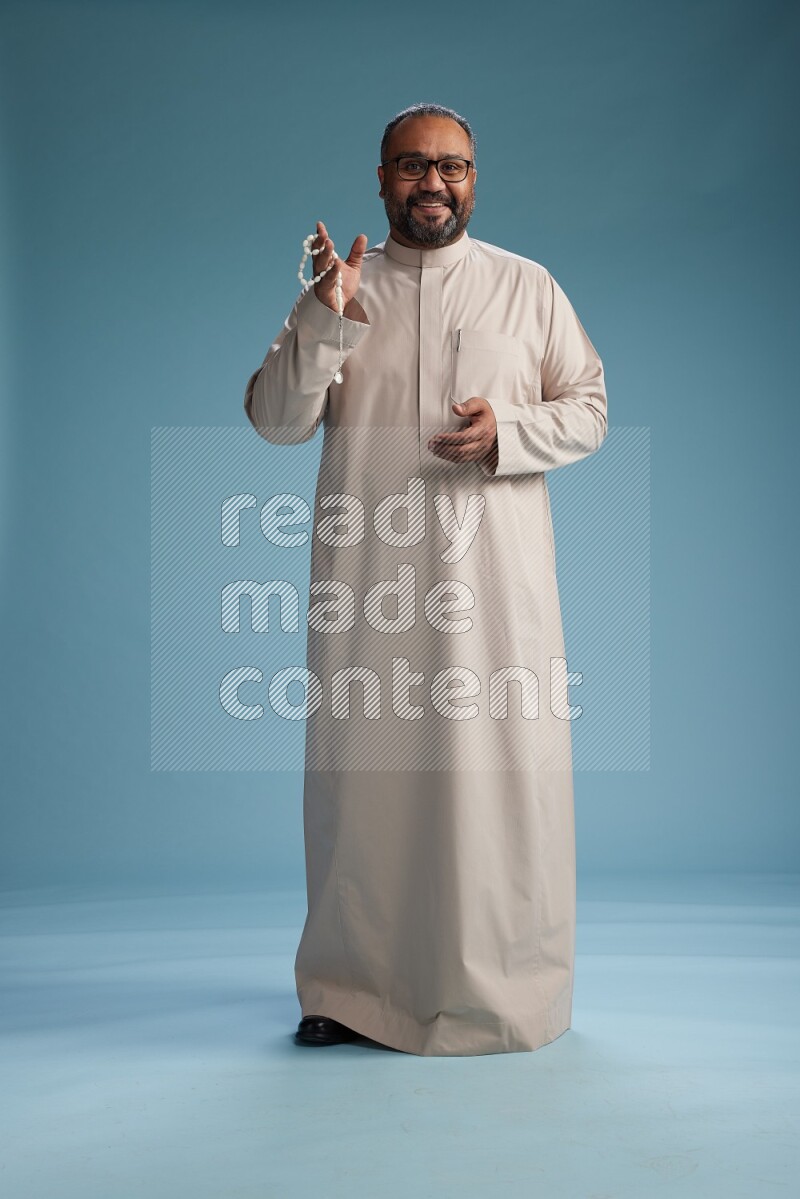 Saudi Man without shimag Standing Interacting with the camera on blue background