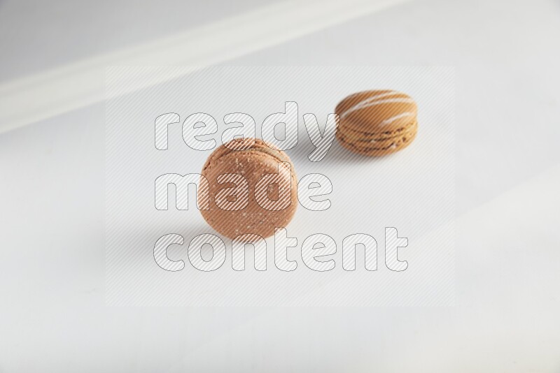45º Shot of of two assorted Brown Irish Cream, and Brown Hazelnuts macarons on white background