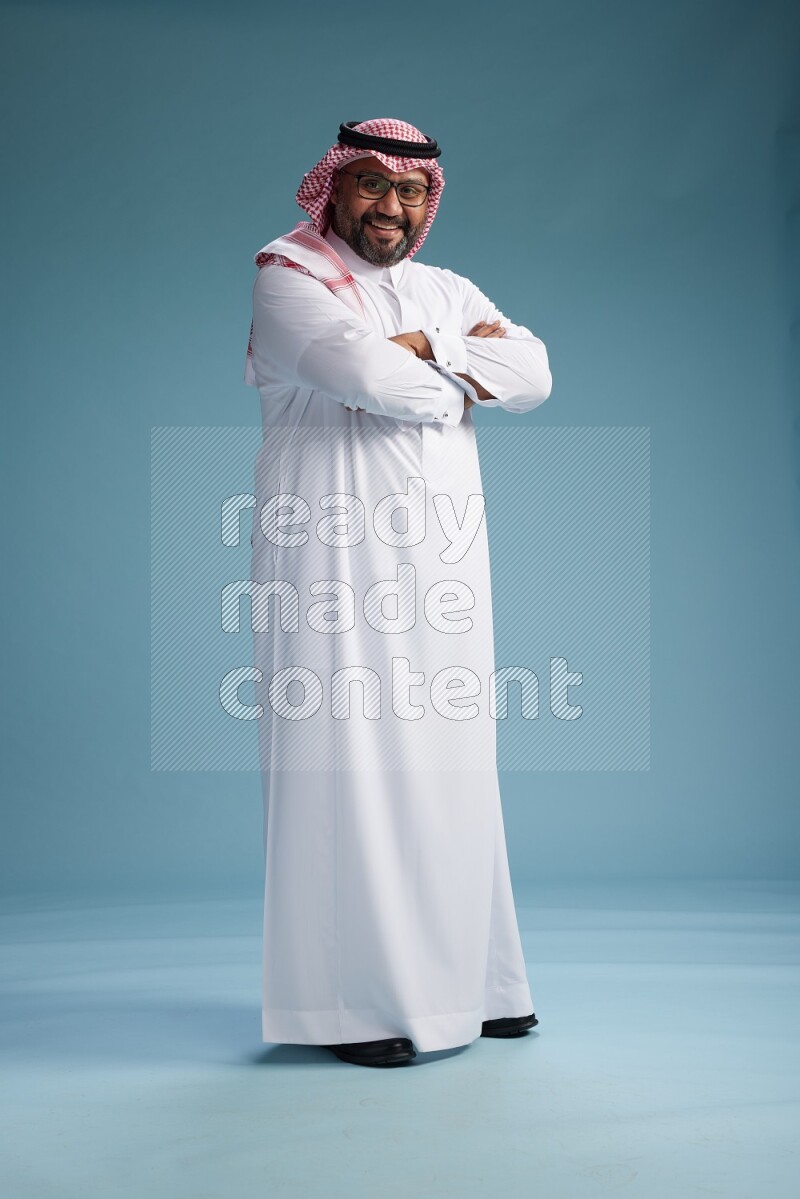 Saudi Man with shimag Standing Interacting with the camera on blue background