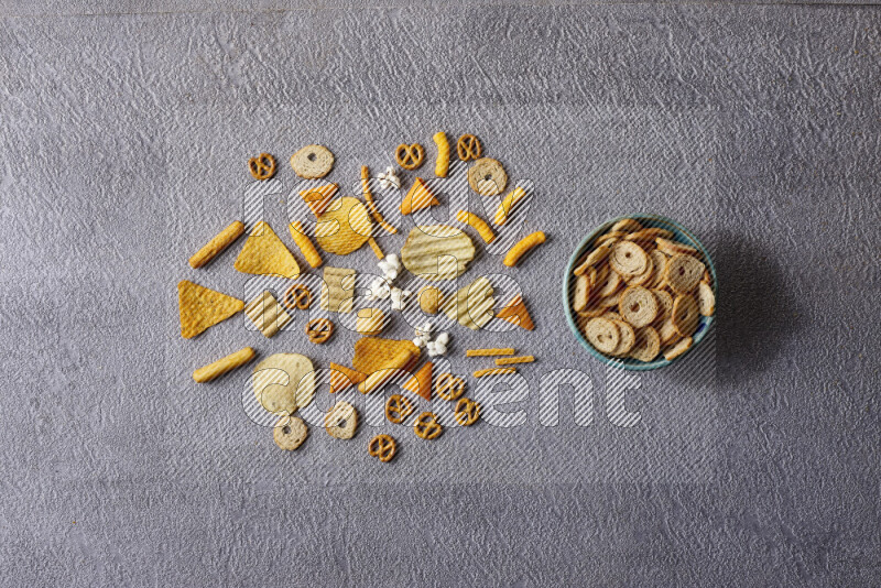 Assorted snacks in pottery bowls on grey background