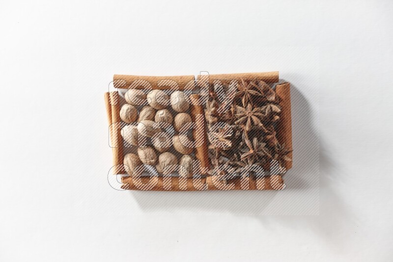 2 squares of cinnamon sticks full of star anise and nutmeg on white flooring