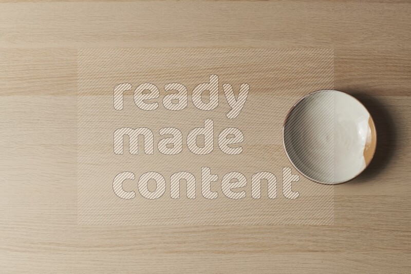 صحن فخاري متعدد الألوان على خلفية خشبية فاتحة