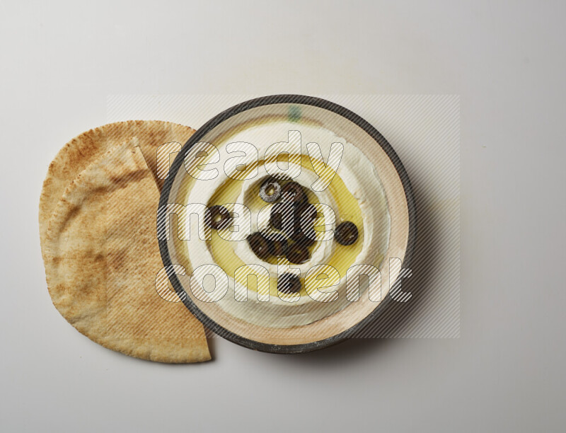 Lebnah garnished with sliced olives in a pottery plate on a white background