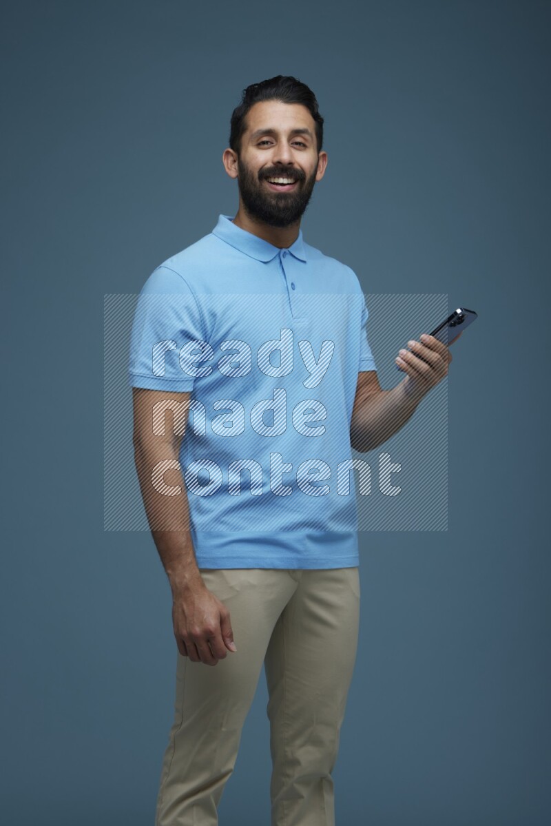 Man posing with a phone in a blue background wearing a Blue shirt