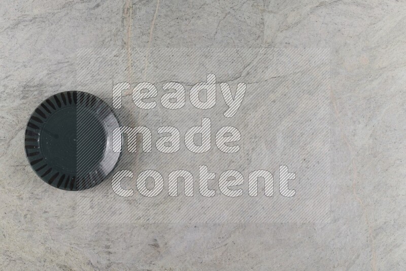 A dark green pottery plate on grey marble background