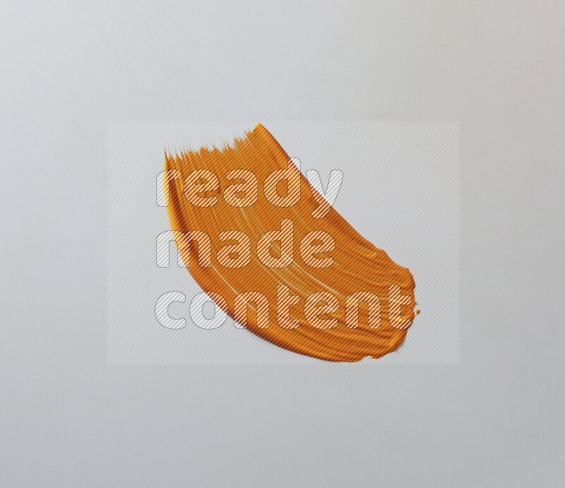 An orange curved painting brush stroke on a white background