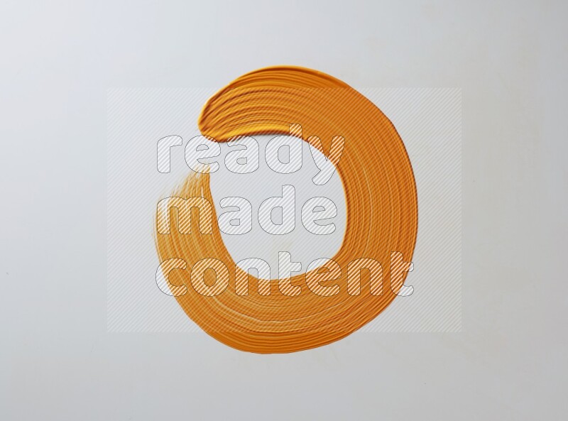 An orange circular painting brush stroke on white background