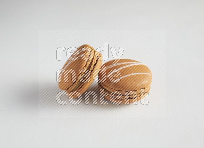 45º Shot of two Brown Irish Cream macarons on white background