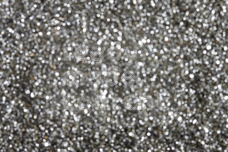 Silver shimmering fragments of glass scattered on a black background