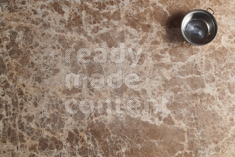 A small copper pot on beige marble background