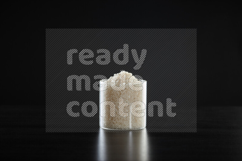 White rice in a glass jar on black background