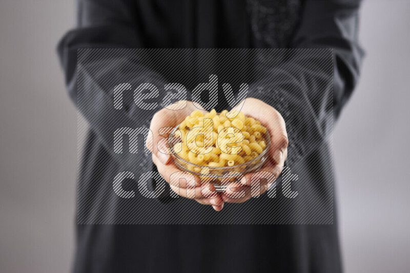 Woman in abaya holding different kinds of pasta in different positions
