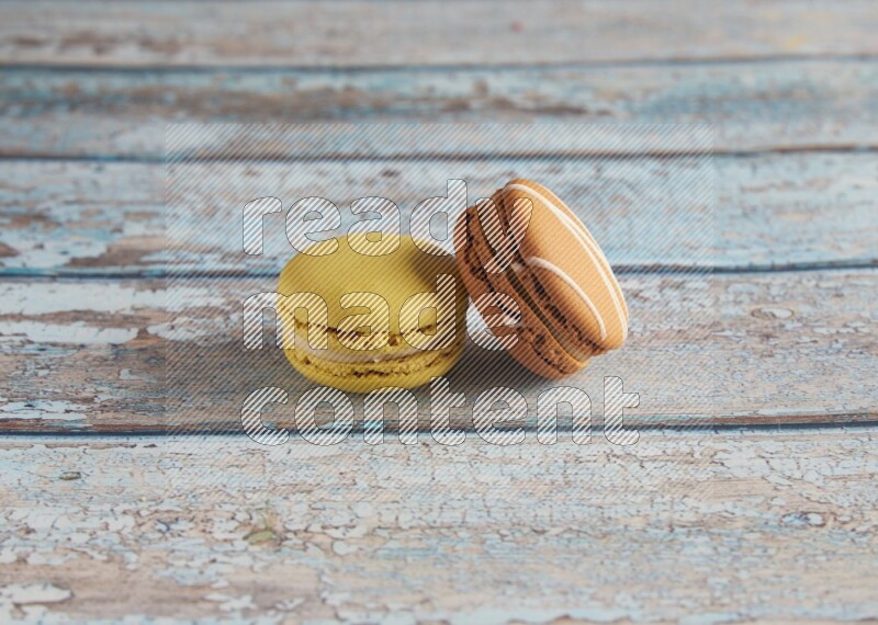 45º Shot of of two assorted Brown Irish Cream, and Yellow Lime macarons on light blue background